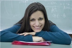 Eine Auszubildende sitzt in einem Klassenzimmer vor einer Tafel.
