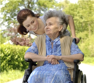 junge Frau schiebt alte Frau im Rollstuhl