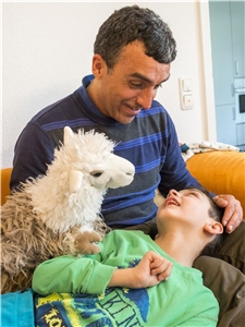 Morten amüsiert sich über das Schaf Behinderter Junge wird von einem Puppenspieler mit Handpuppe unterhalten