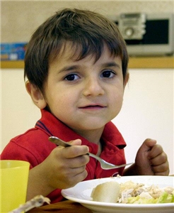 Junge_Kindermittagstisch Kleiner Junge mit dunklen Augen über dem Mittagessen