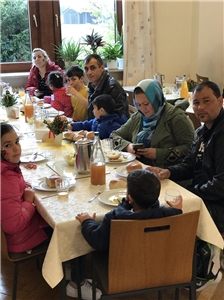 Mehrere Familien sitzen am Tisch bei einer Mahlzeit.