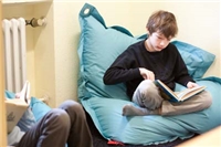 Haus Nazareth Leverkusen Ein Junge sitzt auf einem hellblauen Sitzsack und liest ein Buch