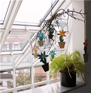 Unser Haus Ein Windspiel aus gebastelten Blumen aus Fotopapier hängt an einem Zweig, der wiederum an einem Fenster aufgehängt ist. Das Bild, das im Caritas-Altenzentrum Heilig Geist aufgenommen worden ist, strahlt Wohnlichkeit und Gemütlichkeit aus.