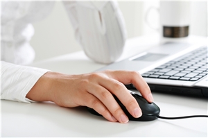 Eine Frau sitzt am Computer, eine Hand an der Maus. Eine Frau sitzt am Computer, eine Hand an der Maus.