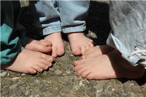 Chancen f�r alle Jugendliche/Kinder Drei Kinder stehen und sitzen vor einem Regal voller Spiele.