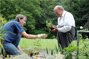Jung hilft alt Junger Mann hilft altem Mann bei der Gartenarbeit
