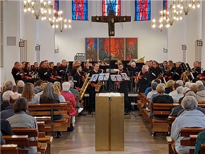Ein Musik-Orchester in schwarzen Uniformen sitzt im Chorraum einer Kirche