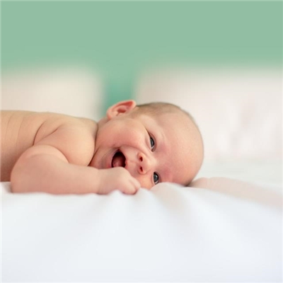 Ein Baby liegt auf einer Decke und lächelt. Ein Baby liegt auf einer Decke und lächelt.