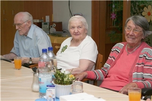 Senioren sitzen gemeinsam am Tisch. 