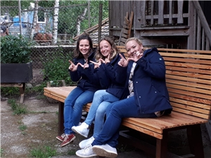 Drei Mitarbeiterinnen tragen die neuen Jacken, sie sitzen auf einer Bank auf dem Gelände des Wilensteiner Hofs. 