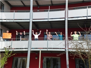 Mutmachaktion: Mitarbeiter und Bewohner winken vom Balkon. 