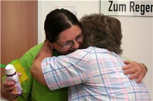 Ein älterer Bewohner von St. Hedwig stützt sich mit dem Arm ab, eine Mitarbeiterin geht mit ihm durch den Gang. 4.2. Grundsätze unserer Arbeit