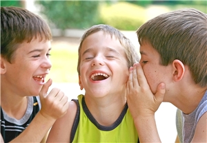 Drei Jungen, die sich etwas ins Ohr flüstern und lachen Drei Jungen, die sich etwas ins Ohr flüstern und lachen