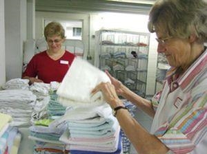 Zwei Frauen legen Handtücher zusammen Zwei Frauen legen Handtücher zusammen