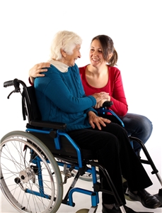 Eine Mitarbeiterin der Altenpflege legt den Arm um eine ältere Frau im Rollstuhl und hält ihre Hand. Eine Mitarbeiterin der Altenpflege legt den Arm um eine ältere Frau im Rollstuhl und hält ihre Hand.