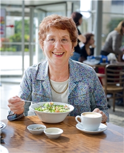 Eine Frau genießt das Mittagessen in Gesellschaft mit anderen. Eine Frau sitzt beim Mittagessen.