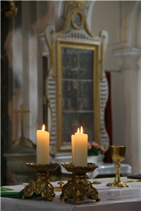 Zwei Kerzen in einer Kirche, im Hintergrund ein Altar