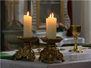Vier Kerzen in einer Kirche, dahinter ein Altar