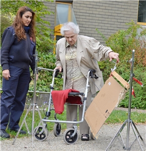 Eine Bewohnerin mit Rollator versucht, übungsweise eine Tür zu öffnen und mit ihrem Rollator hindurchzugehen, assistiert von einer Trainerin. Rollatoren-Training 1