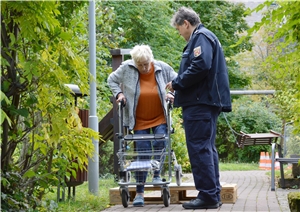 Eine Bewohnerin versucht mit Hilfe des Trainers mit ihrem Rollator ein Hindernis zu überwinden. Rollatoren-Training 2