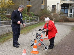 Polizeihauptkommissar Matthias Michel begleitet eine Seniorin, die mit ihrem Rollator zwischen Hütchen hindurchfahren muss. 