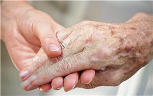 Eine Altenpflegerin hält die Hand einer Bewohnerin. 