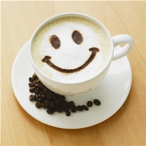 Eine Kaffeetasse mit einem lächelnden Gesicht aus Kaffeepulver im Milchschaum.