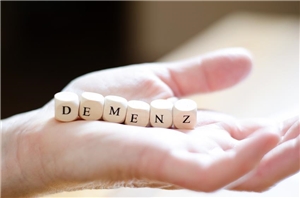 Auf einer ausgestreckten Hand sind Buchstabenwürel gelegt. Sie ergeben das Wort Demenz.