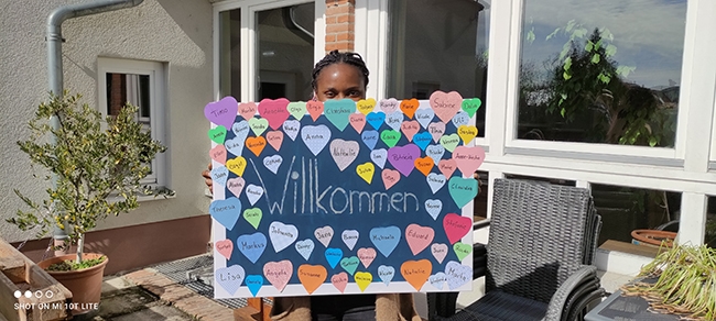 Die Leiterin der Stabstelle Vielfalt Corine Ngahan mit Plakat mit vielen bunten aufgeklebten Herzen mit Namen (Caritasverband Darmstadt e. V.)