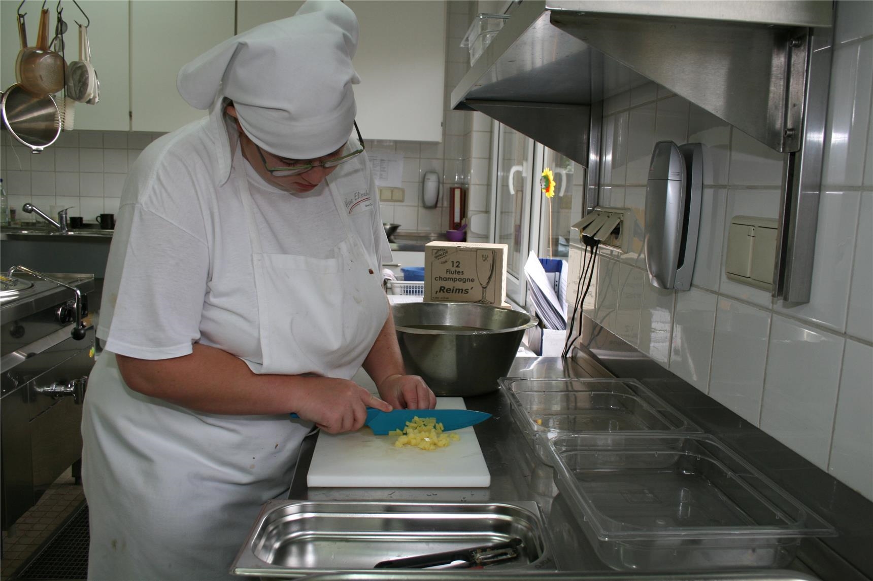 Eine junge Frau in Berufskleidung schneidet Möhren in einer Küche. (BBZ Haus Elisabeth/Caritasverband Trier)