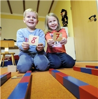 Ein Junge und ein Mädchen halten Holztäfelchen mit Zahlen in der Hand / D. Wäsche