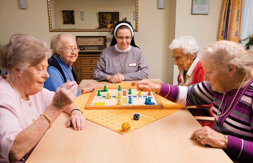 Vier Bewohner spielen mit einer Nonne Mensch-ärgere-Dich-nicht 
