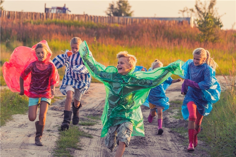 Rennende, fröhliche Kinder in Umhängen auf einem Feld