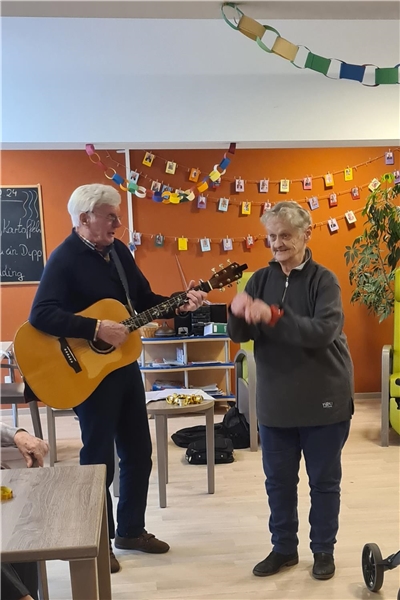 Ein Senior spielt Gitarre eine Seniorin tanzt dazu.