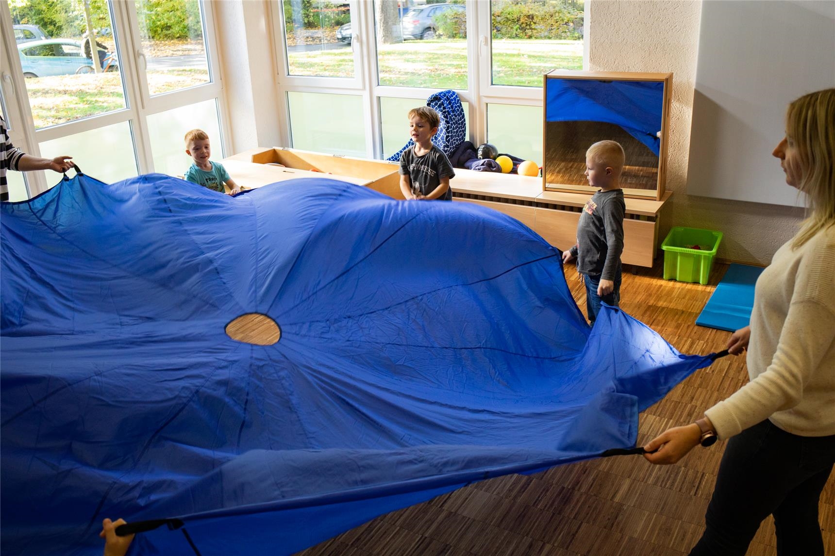 Kinder spielen gemeinschaftlich mit einem großen blauen Tuch. 