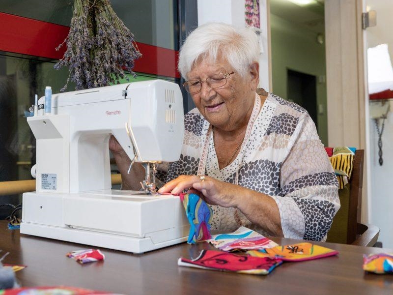 Eine Seniorin näht mit einer Nähmaschine 