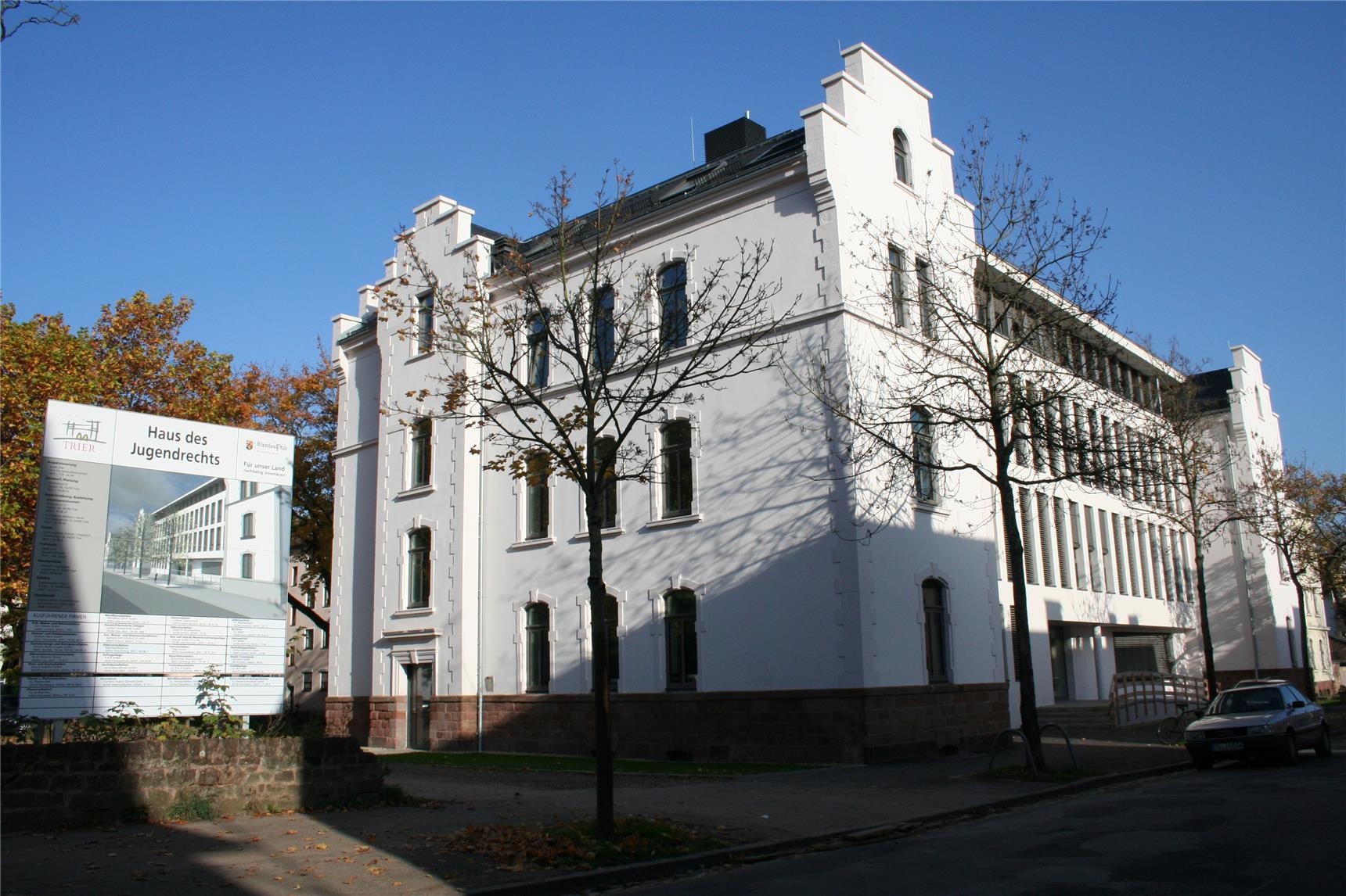Blick auf ein großes, weißes Gebäude – daneben ein Schild mit der Aufschrift „Haus des Jugendrechts“. (Quartiersmanagement Trier-West/Caritasverband Trier e. V.)