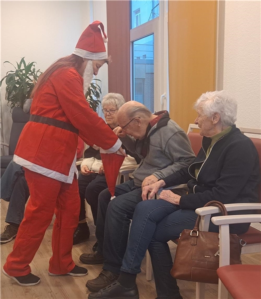 Person im Nikolauskostüm verteilt Gaben aus einem Sack an Senior:innen