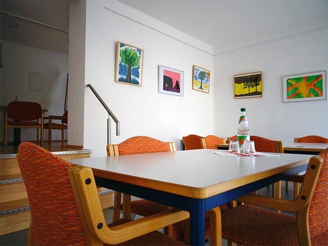 Besprechungsraum mit Tischen und Stühlen und Wasserfarb-Bildern an den Wänden (Caritasverband Darmstadt e. V.)