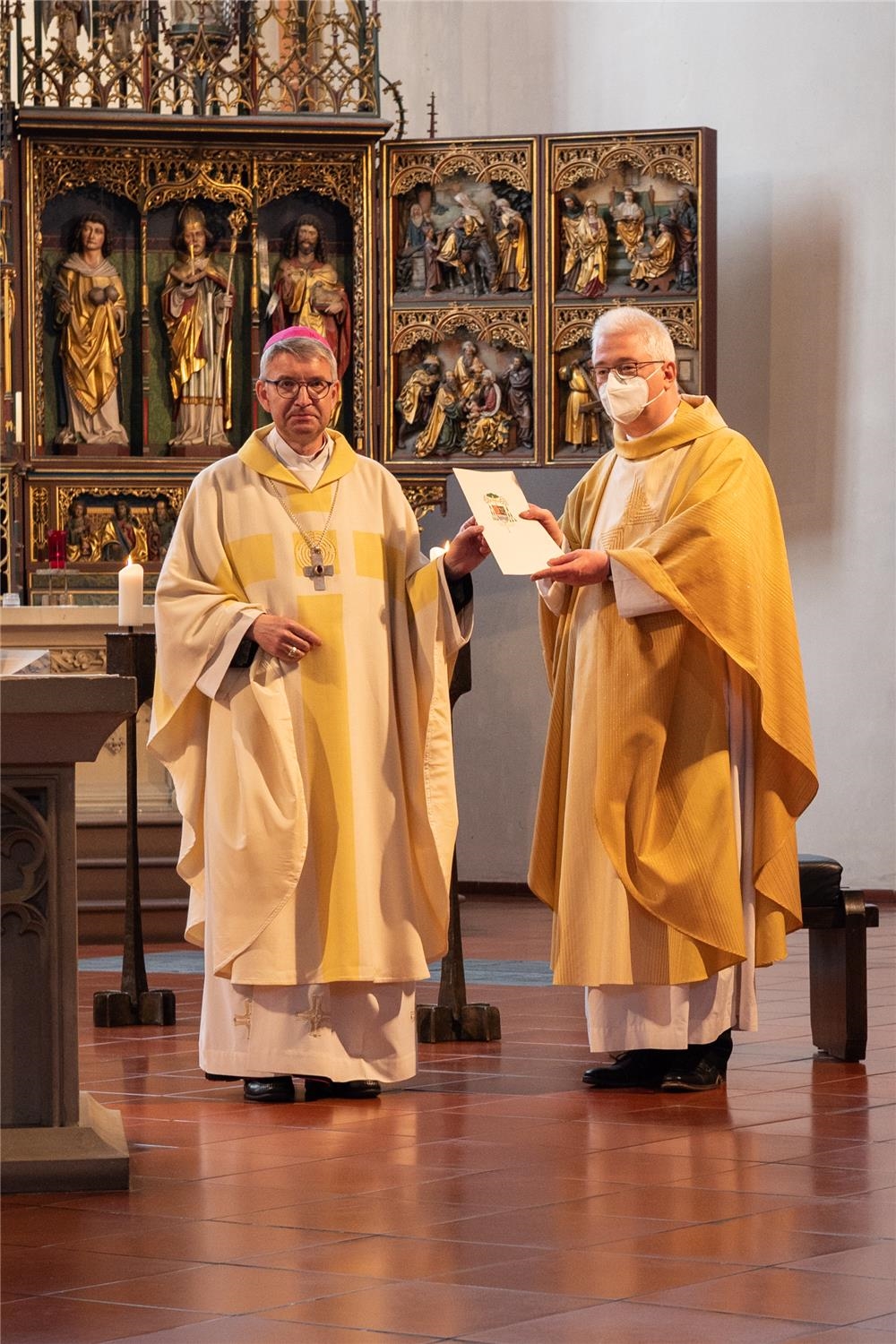 Bischof übergibt Urkunde an Priester (Quelle: Anja Schaal )