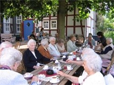 Viele Bewohner des Altenzentrums sitzen im Garten und trinken miteinander Kaffee.