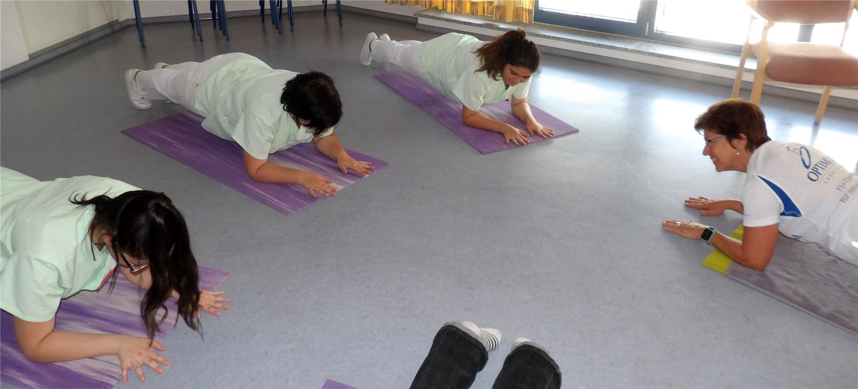 Mitarbeiterinnen machen auf dem Boden Yoga-Übungen 