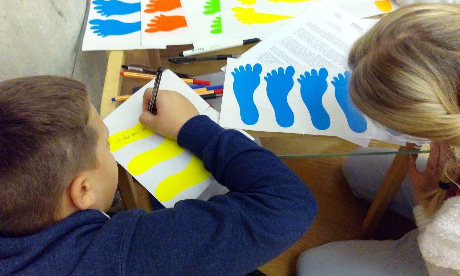 Kinder schreiben auf Fußabdrücke (Kinderstiftung)