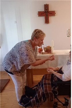 eine Mitarbeiterin des Altenzentrums reicht einer Bewohnerin den Leib Christi / Caritas Fulda
