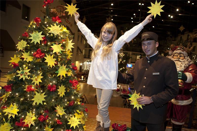 Christina, 8 Jahre, steht vor einem Weihnachtsbaum 
