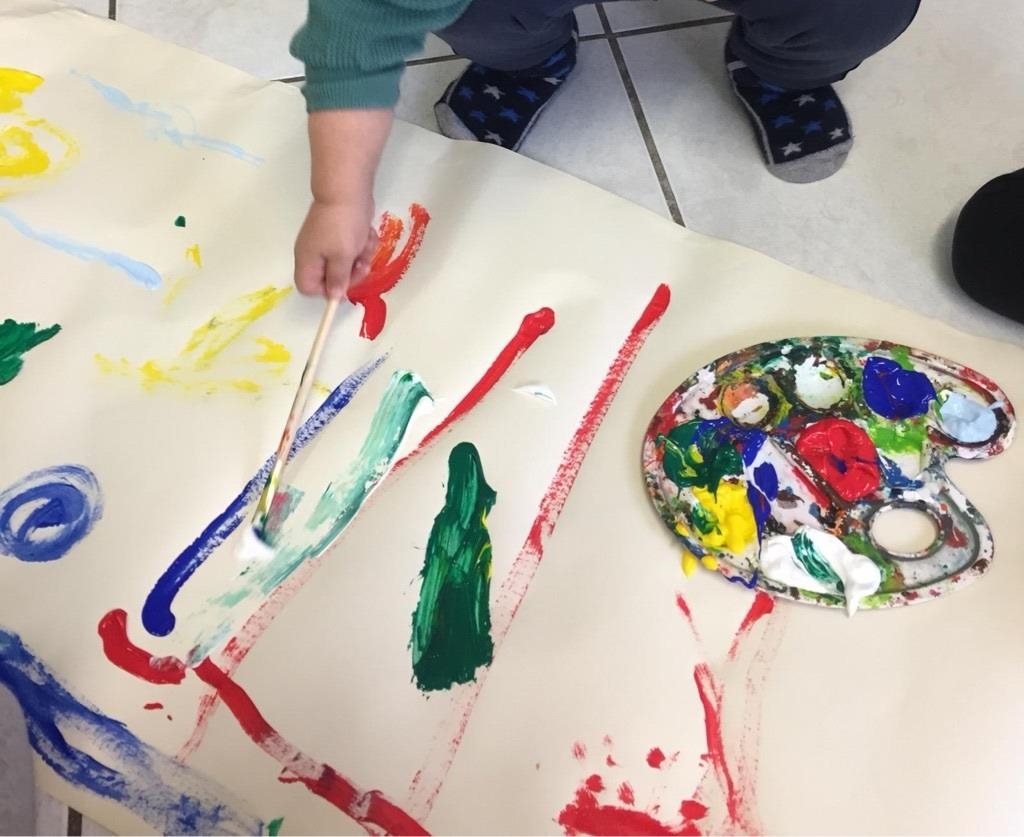 Ein Kind malt mit Pinsel und Farbe 