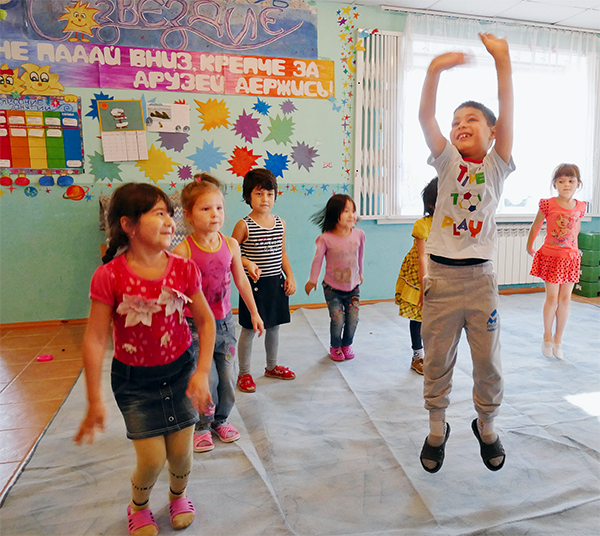 Eine Gruppe russischer Kinder steht in einem bunt gestalteten Raum und und hüpfen in die Luft (Christian Heidrich)