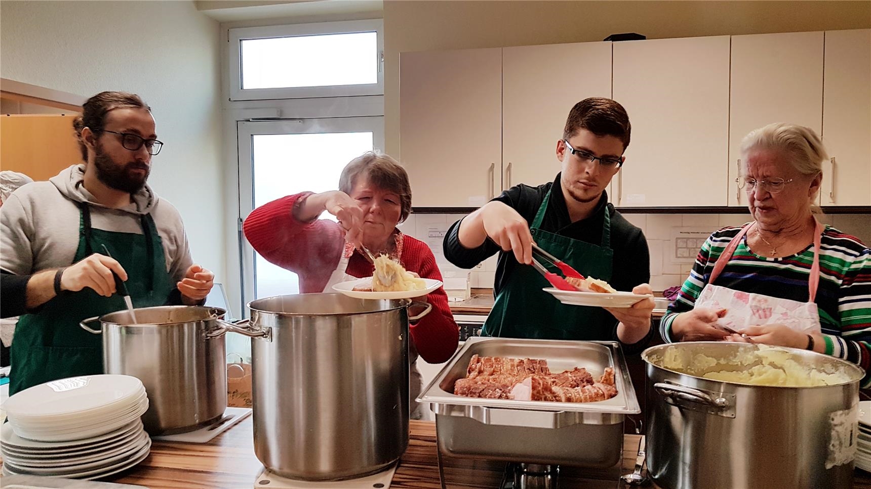 Vier ehrenamtliche Helfer kümmern sich um die Essensausgabe (Foto: Katholische Kirche St. Bonifaz)