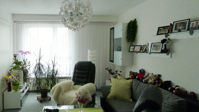 Wohnzimmer mit moderner Kugellampe, Sessel und Couch im Servicewohnen. 