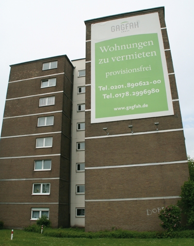 Die Fassade eines Hauses im Duisburger Stadtteil Bonnefeld mit einem Werbebanner des Wohnungsunternehmens (Harald Westbeld)